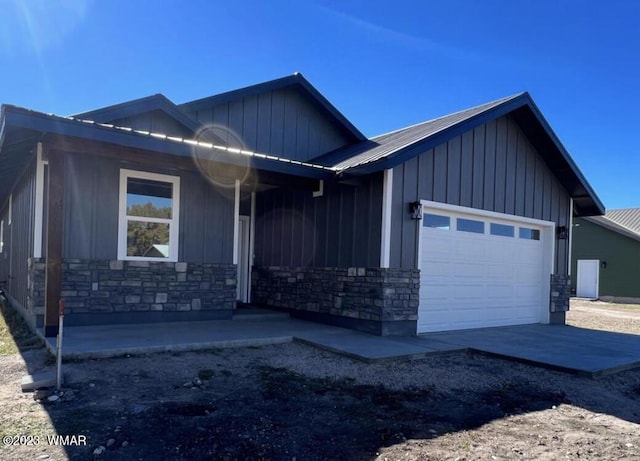 view of front of property featuring a garage, stone siding, and board and batten siding