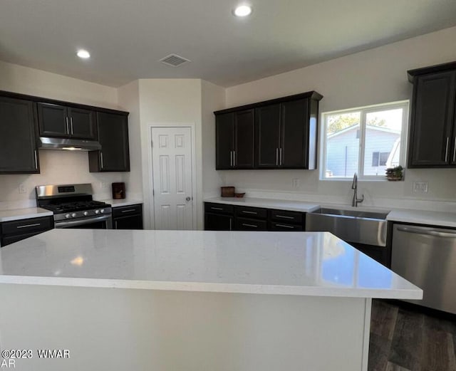 kitchen featuring a center island, visible vents, appliances with stainless steel finishes, a sink, and under cabinet range hood