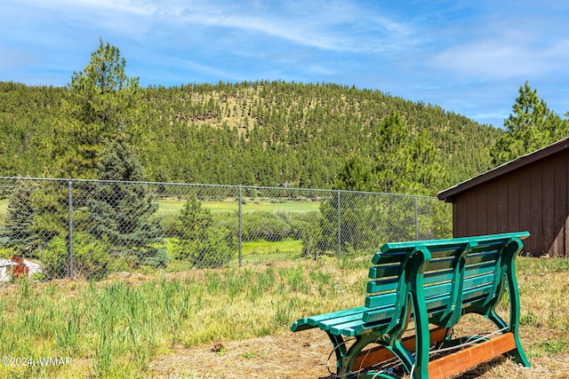 view of yard with a playground, a wooded view, and fence