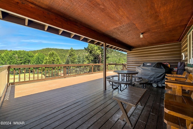 deck with grilling area and a view of trees