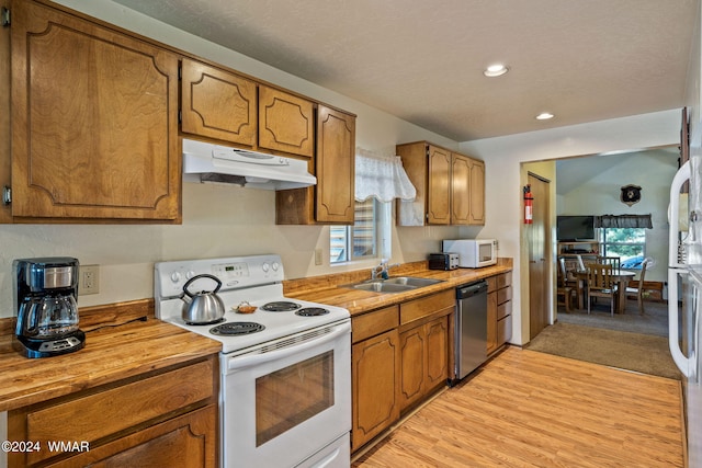 kitchen with white appliances, brown cabinets, a sink, and under cabinet range hood