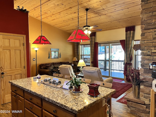 kitchen featuring open floor plan, light stone counters, dark wood finished floors, and a center island