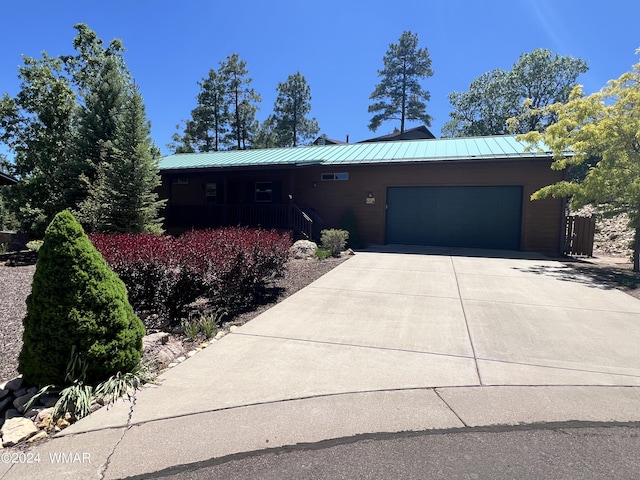 view of front facade with metal roof, driveway, a standing seam roof, and an attached garage