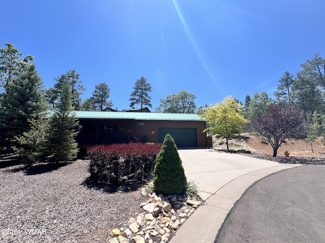 view of front facade with an attached garage, a standing seam roof, metal roof, and concrete driveway