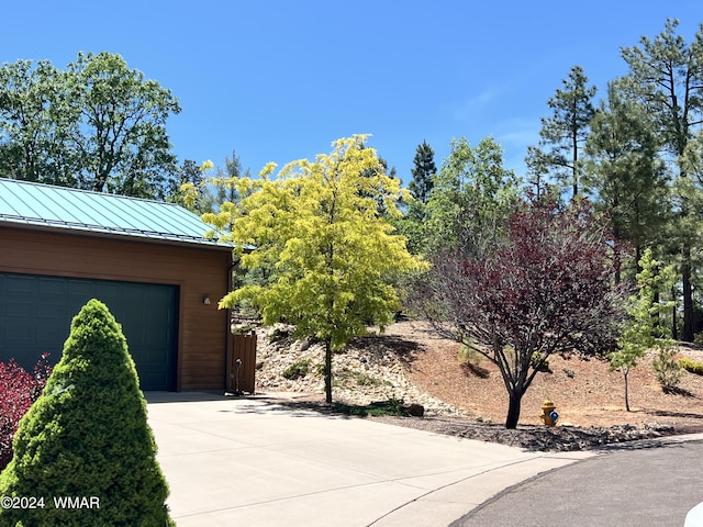 view of front of house with a garage, a standing seam roof, metal roof, and concrete driveway