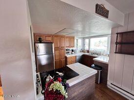 kitchen featuring baseboard heating, freestanding refrigerator, and dark wood-style floors
