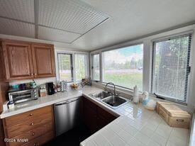 kitchen with tile patterned floors, brown cabinets, stainless steel dishwasher, and a sink