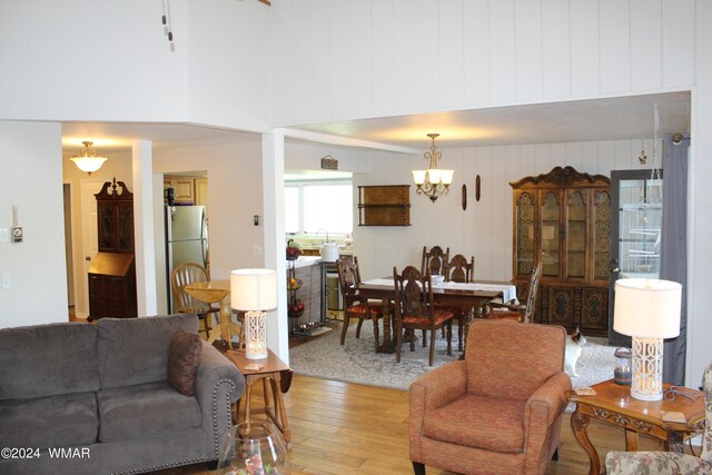 living room featuring a high ceiling, light wood finished floors, and a notable chandelier