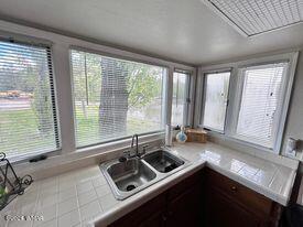 kitchen featuring tile patterned floors, dark brown cabinetry, a sink, and tile counters