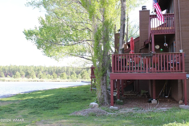 view of yard with a deck with water view and a view of trees