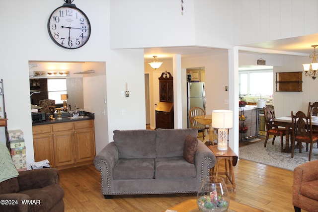 living area with a towering ceiling, light wood-style floors, and a healthy amount of sunlight