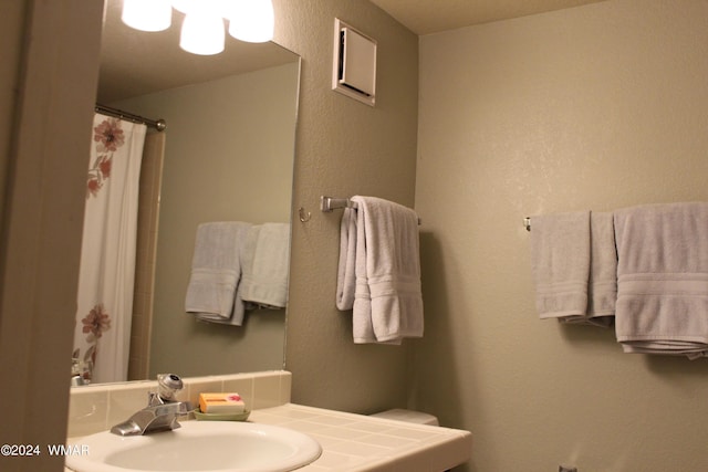 full bath featuring a shower with shower curtain and a sink