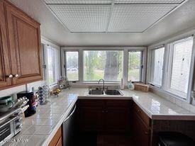 kitchen with brown cabinets, stainless steel dishwasher, a sink, and plenty of natural light