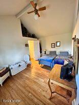 bedroom with ceiling fan, wood finished floors, and lofted ceiling with beams