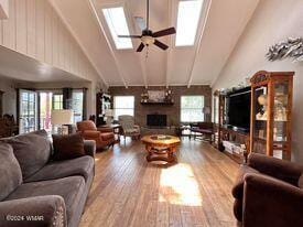 living area featuring a skylight, high vaulted ceiling, plenty of natural light, and a fireplace