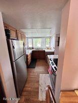 kitchen with dark wood-type flooring, light countertops, and freestanding refrigerator