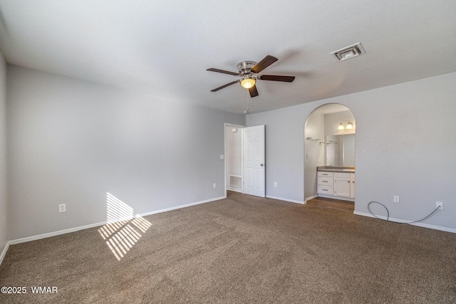 unfurnished bedroom with baseboards, visible vents, arched walkways, and carpet flooring