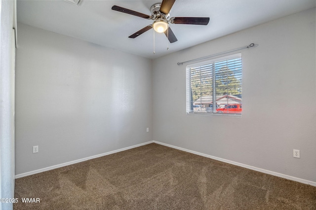 carpeted spare room with a ceiling fan and baseboards