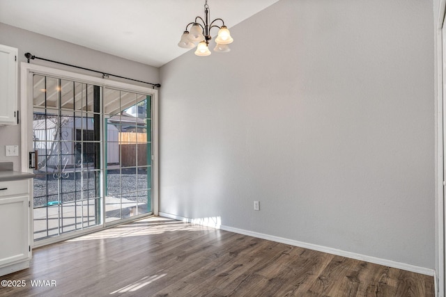 unfurnished room featuring a chandelier, wood finished floors, lofted ceiling, and baseboards