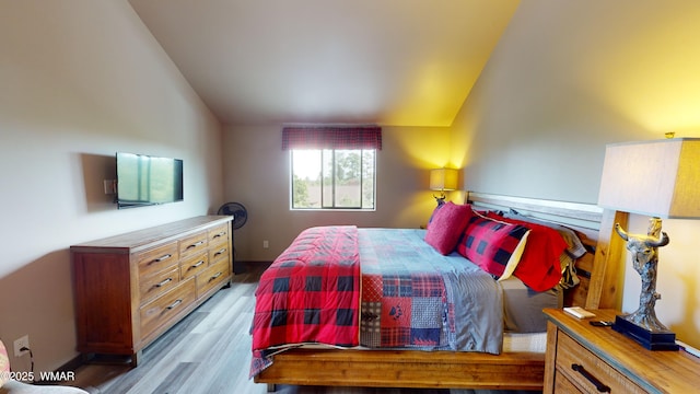 bedroom with wood finished floors and lofted ceiling