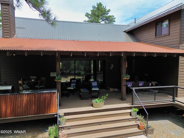 back of property featuring a wooden deck, a chimney, and metal roof