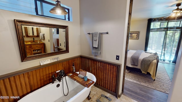bathroom featuring a sink, a ceiling fan, a freestanding tub, and wainscoting