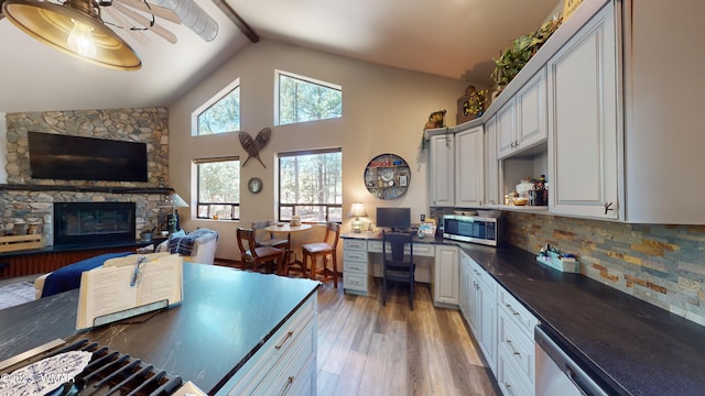 kitchen featuring dark countertops, built in desk, light wood-style flooring, stainless steel appliances, and decorative backsplash