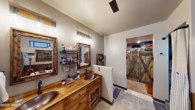 full bath featuring double vanity, baseboards, visible vents, and a sink