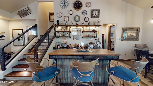 bar with stairway, indoor bar, and wood finished floors