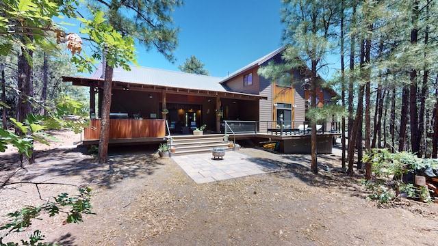 back of property featuring a deck, metal roof, and a patio area