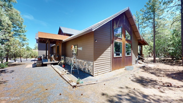 view of side of home featuring metal roof and stone siding