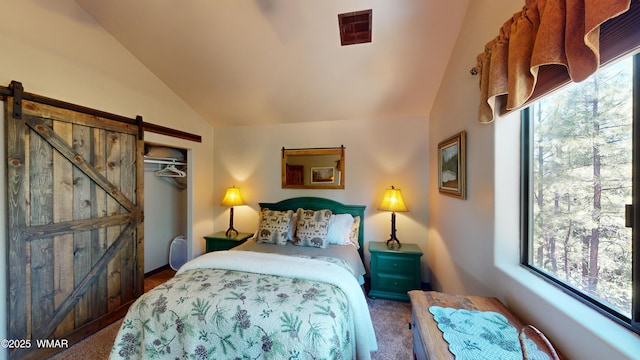 bedroom featuring visible vents, a closet, lofted ceiling, a barn door, and carpet