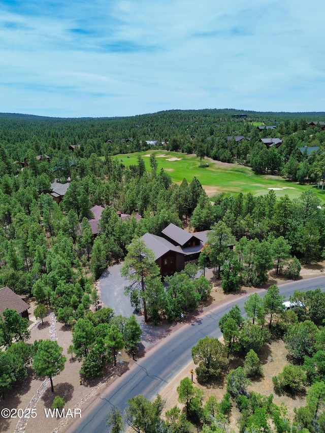 drone / aerial view featuring view of golf course and a view of trees