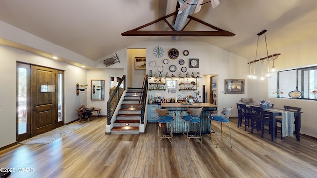 interior space with plenty of natural light, dark wood-style flooring, bar area, and high vaulted ceiling