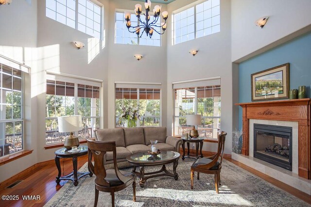 1961 S Canyon Ridge Trl, Show Low, AZ 85901 - living room featuring wood finished floors, a towering ceiling, a glass covered fireplace, a chandelier, and baseboards