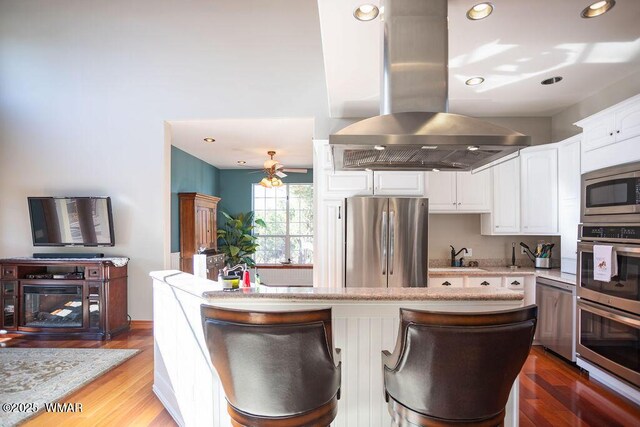 1961 S Canyon Ridge Trl, Show Low, AZ 85901 - kitchen featuring appliances with stainless steel finishes, island exhaust hood, white cabinetry, a sink, and wood finished floors