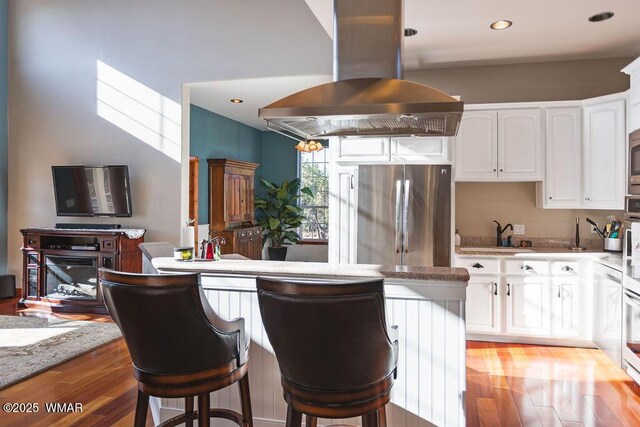 1961 S Canyon Ridge Trl, Show Low, AZ 85901 - kitchen with stainless steel appliances, island range hood, light wood finished floors, white cabinets, and a breakfast bar