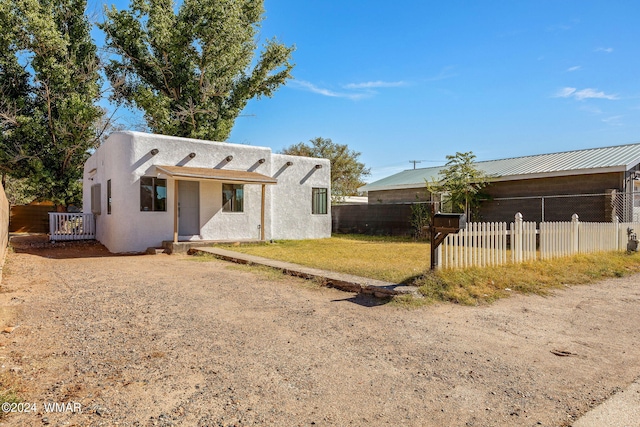 pueblo-style house featuring fence private yard, a front lawn, and stucco siding