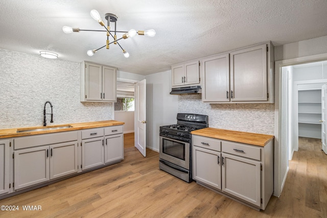 kitchen featuring wood counters, a sink, gas range, and under cabinet range hood