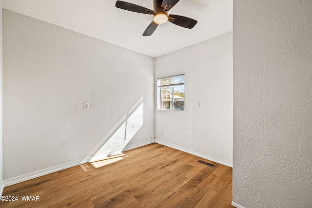 spare room with visible vents, a textured wall, baseboards, and wood finished floors