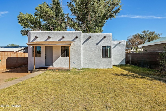 view of front of home featuring a fenced backyard, a front lawn, and stucco siding