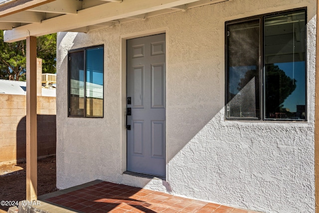 doorway to property with a patio, fence, and stucco siding