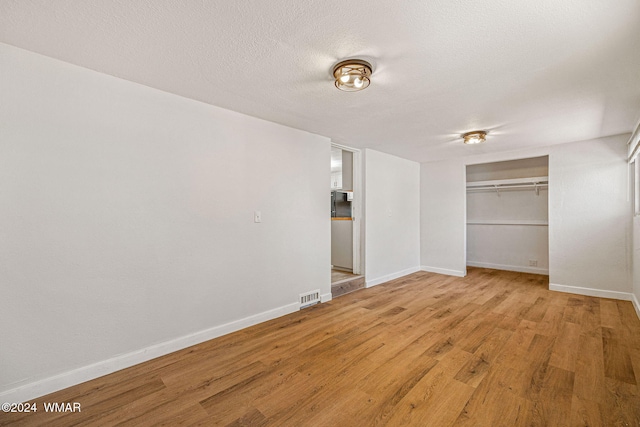 interior space with baseboards, visible vents, wood finished floors, a textured ceiling, and a closet