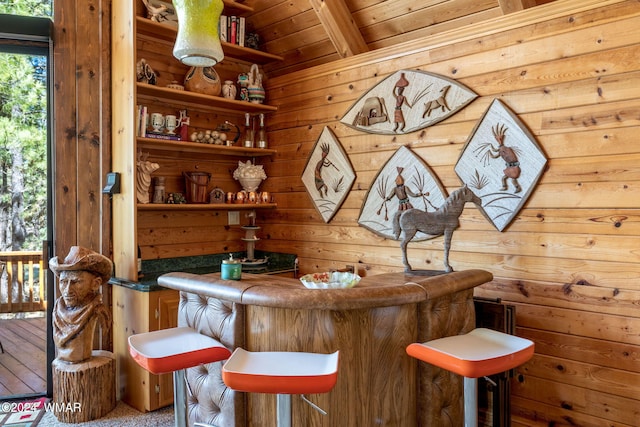 bar with a dry bar, beamed ceiling, wooden ceiling, and wooden walls