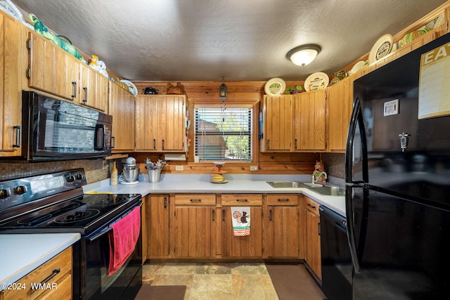 kitchen featuring brown cabinets, stone finish floor, light countertops, and black appliances