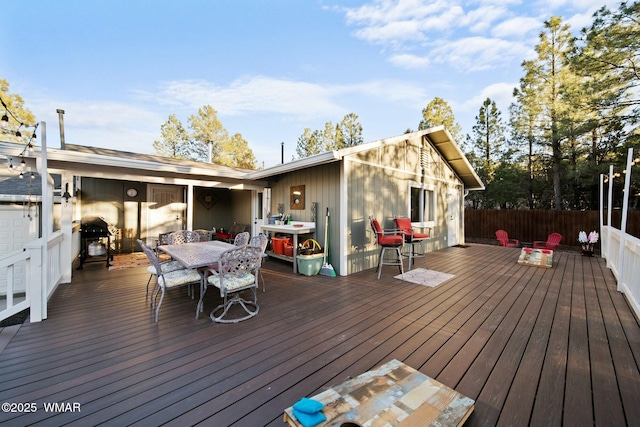 deck featuring outdoor dining space, fence, and grilling area