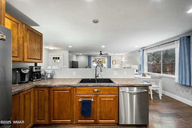 kitchen with brown cabinets, dark wood-style flooring, stainless steel appliances, and a sink