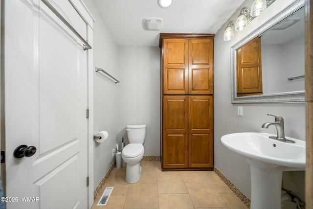 bathroom with baseboards, visible vents, toilet, tile patterned floors, and a sink