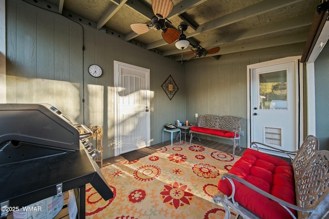 interior space featuring wood walls, beam ceiling, and a ceiling fan