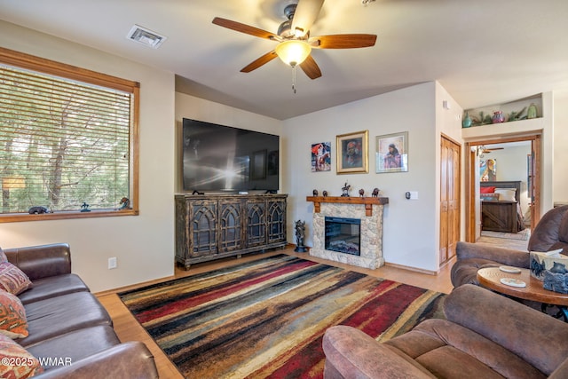 living area featuring ceiling fan, a fireplace, wood finished floors, and visible vents